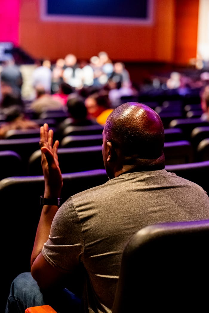 Man in auditorium engaged in a live presentation. Vibrant setting.
